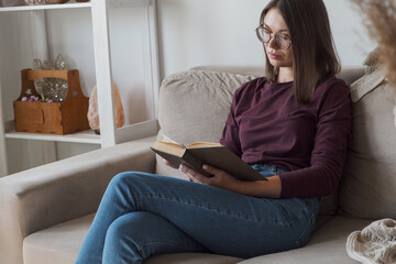 Woman reading book sitting in sofa at home