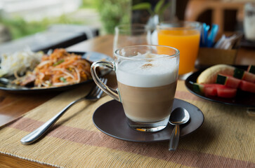 Transparent glass cup of coffee latte on table in the restaurant. Copy space