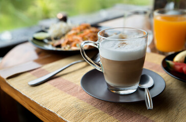 Transparent glass cup of coffee latte on table in the restaurant. Copy space