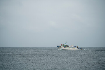 Fishing and pleasure boats sailing along the sea coast, during the summer on a cloudy day