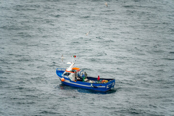 Naklejka premium Fishing and pleasure boats sailing along the sea coast, during the summer on a cloudy day