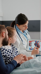 Pediatric cardiologist woman doctor explaining heart illness using tablet with medical cardiogram...