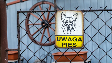 stara tabliczka uwaga pies powieszona na siatce ogrodzenia - obrazy, fototapety, plakaty