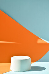 The podium is an orange-blue background with a geometric figure made of concrete. A scene with a showcase made of cement. Minimalistic background. Presentation of cosmetics.