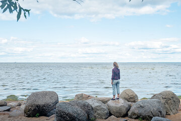Woman looks at the Gulf of Finland in the park of the city of Peterhof in Russia