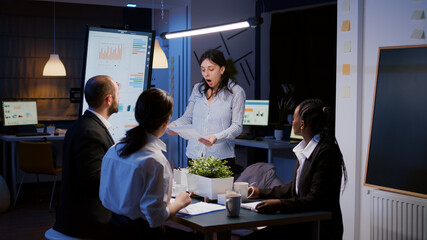 Nervously furious irritated businesswoman screaming while overworking in meeting office room throwing corporate paperwork late at night. Overworked teamwork solving company solution in evening