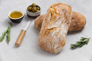 Artisan sourdough ciabatta bread with olives and rosemary on a concrete table. Freshly baked...