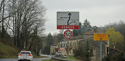 Panneau de signalisation routière :  avertissement danger et directions à l'entrée d'un village.