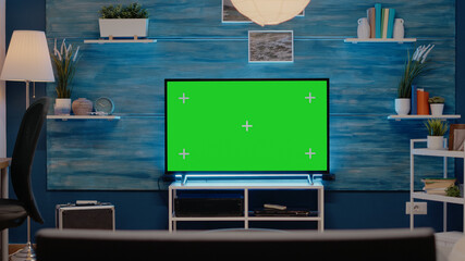 Empty room with green screen on television in living room at modern home. Tv display with mockup template with chroma key concept for copy space isolated digital background