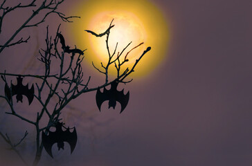 Halloween. Bats hang from the branches of trees against the background of a full moon.