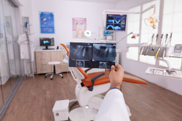 Radiologist dentist doctor holding medical teeth radiography working in stomatology hospital office examination room. Specialist orthodontist analyzing tooth jaw after oral dental surgery