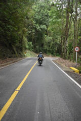 young man driving down the road in the daytime 