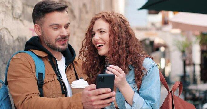 So fun. Waist up portrait view of the curly ginger woman drinking coffee and discussing something with her best friend at the city street. Stock video