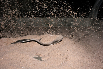 Spoon falling over cocoa powder