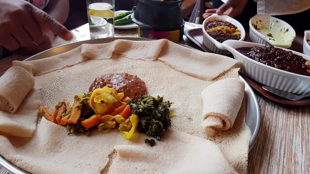 Serving an injera meal, with shiro, lentils, egg and a variety of vegetables