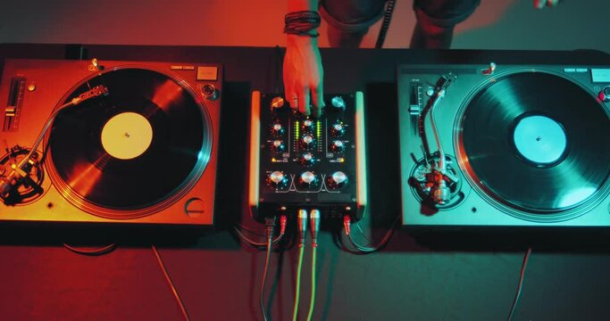 Deejay playing electronic music on dj mixer controller desk in nightclub party. Dj touching vinyls, sliders. Top view