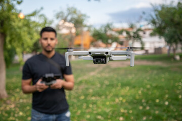 Hombre joven piloteando un mini dron en un parque