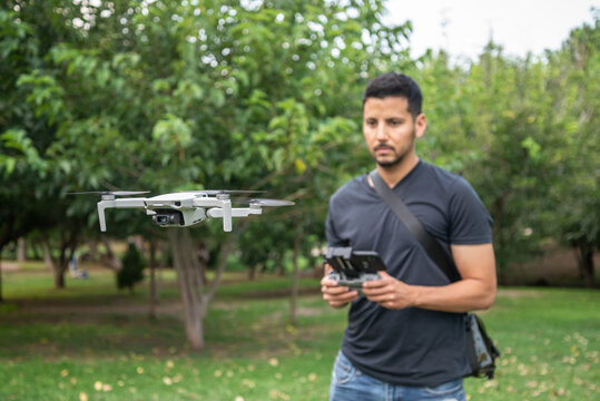 Hombre joven piloteando un mini dron en un parque
