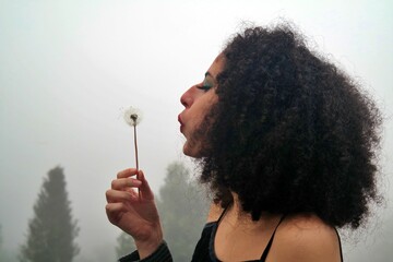 dandelion young brazilian woman afro hair in the cold with fog.