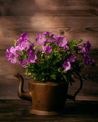 Still life on a table with flowers, books, tea pot and dark background