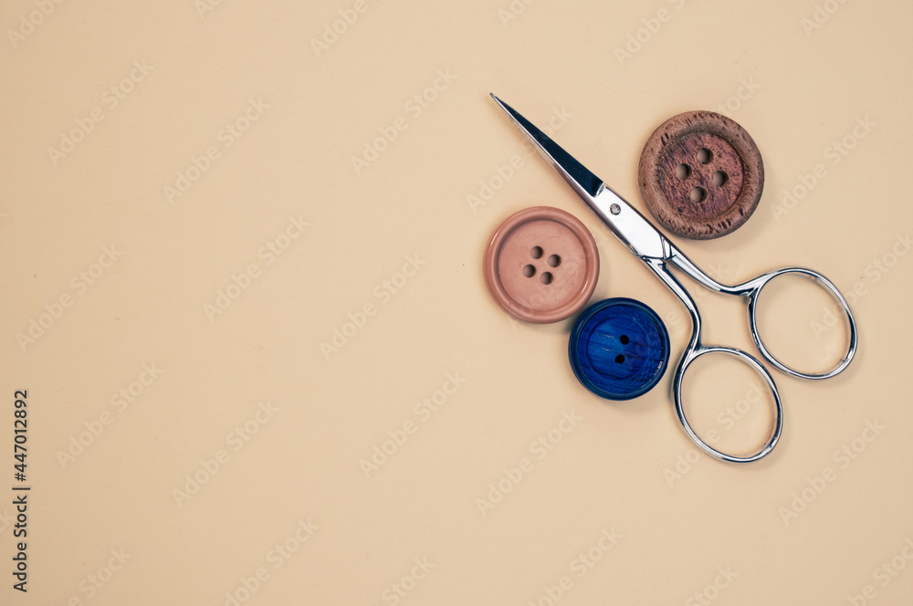 Poster top view of scissors and buttons isolated on light brown background
