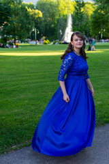 Prom girl spinning in a modern and elegant blue dress. Adorable and fashionable outfit. Beautiful photo from the nature for graduation ceremony