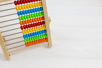 Wooden colorful abacus on wooden background. Back to school, education. Tool for calculation in kindergarten, preschool