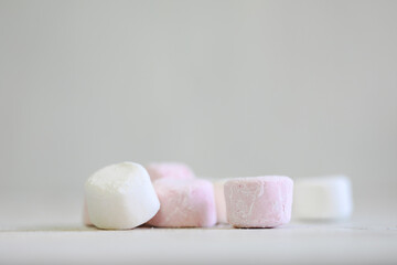 Pink and white marshmallows on plain white background with copy space