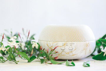 White essential oil diffuser surrounded by fresh jasmine flowers on white background with copy space