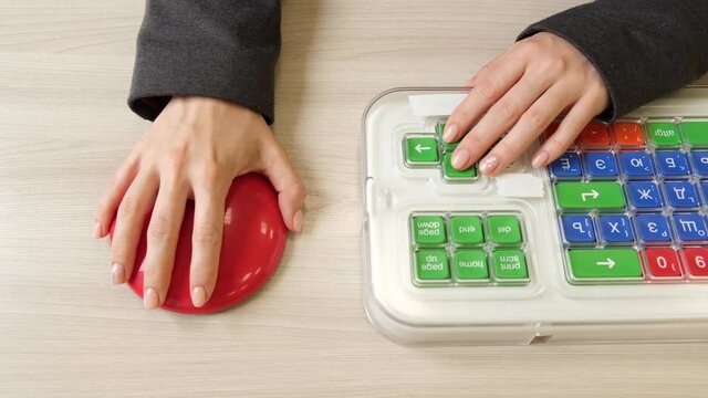 Woman with cerebral palsy works on a specialized computer mouse.