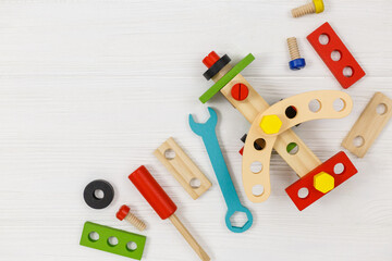 A colorful wooden building kit for children on wood. Set of tools on white wooden table. Games and tools for kids in kindergarten, preschool or daycare. Natural, eco-friendly toys.