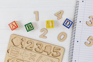 Wooden blocks with ABC letters, open notepad, numbers on wooden table.  Games and tools for kids in preschool or daycare. Education, back to school concept