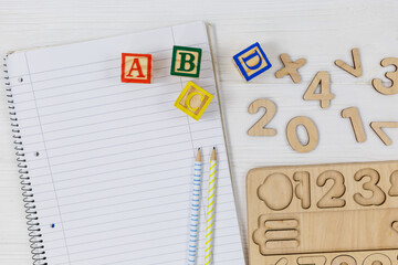 Wooden blocks with ABC letters, open notepad, numbers on wooden table.  Games and tools for kids in preschool or daycare. Education, back to school concept