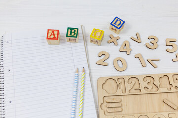Wooden blocks with ABC letters, open notepad, numbers on wooden table.  Games and tools for kids in preschool or daycare. Education, back to school concept