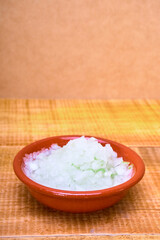 shredded onion on a earthenware plate on a wooden surface and wooden background. mexican food concept. copy space for advertising.