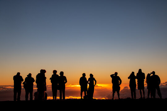 People watching the sunset above the clouds at Haleakalā in Maui, Hawaii.