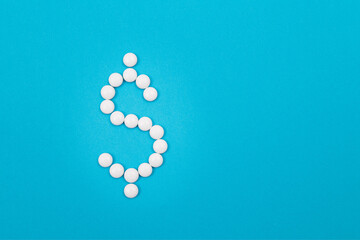 Global Pharmaceutical Industry and Medicine Business - Dollar Symbol Made from White Pills Lying on Blue Background