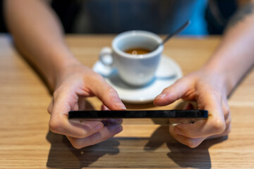female hands with a cellphone on a table with coffee
