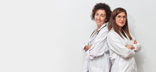 Portrait of two female doctors back to back looking at camera