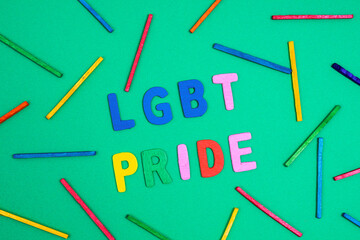 Happy pride written with colored letters on a green surface	