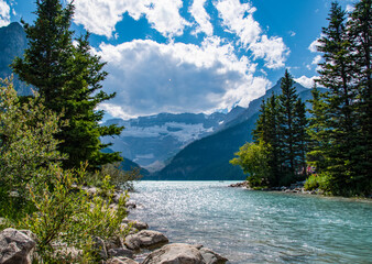 A small river leads into the glacial waters of Lake Louise as they bask in the bright sunlight,...