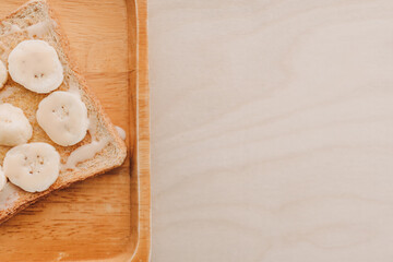 Homemade Banana Toast for summer breakfast on wooden plate.