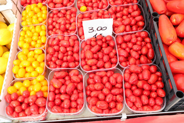 vegetable market with many red ripe cherry tomatoes for sale