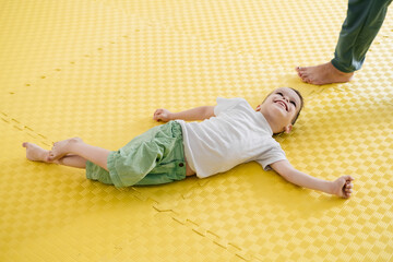 Happy child on the mat in child rehabilitation center. Boy with cerebral palsy smiling....