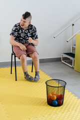 Happy teenage child play with balls in rehabilitation center. Boy with cerebral palsy smiling,...
