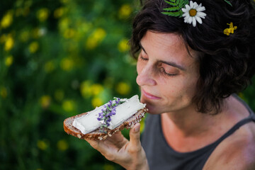happy woman with brown flowery hair eating and biting vegan cheese substitute whole grain bread...