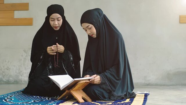Portrait of an Asian Muslim women in a daily prayer at home reciting Surah al-Fatiha passage of the Qur'an in a single act of Sujud called a Sajdah or prostration