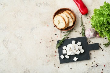 Board with delicious pieces of feta cheese on light background