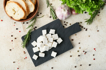 Board with delicious pieces of feta cheese on light background