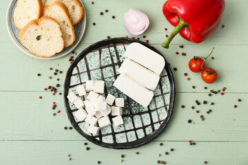 Plate with delicious pieces of feta cheese on color wooden background
